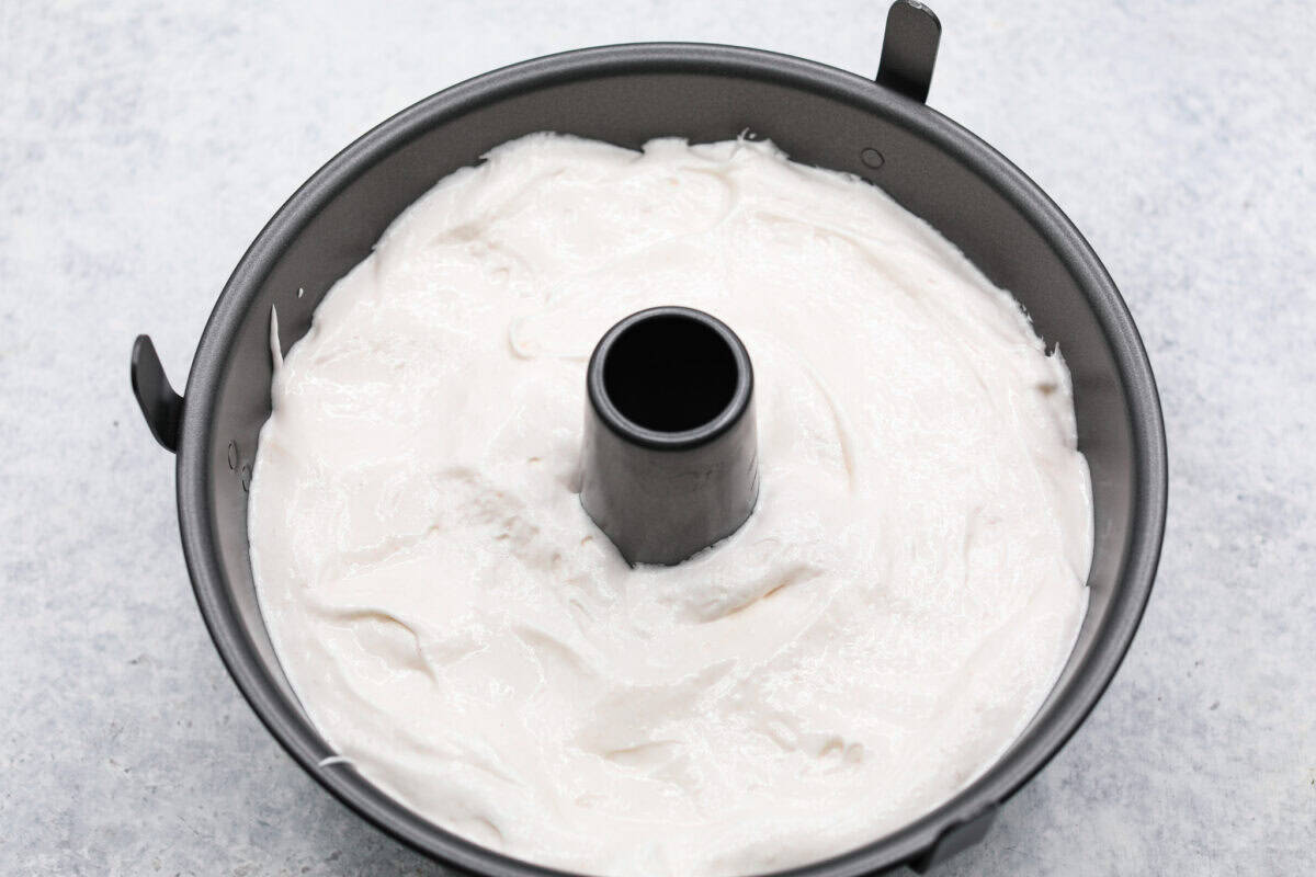 This light & fluffy Angel Food Cake is like a slice of heaven on a plate! It's delicious all on its own but absolutely divine topped with sweetened whipped cream and fresh berries or lemon curd! Overhead shot of angel food cake batter in tube pan.