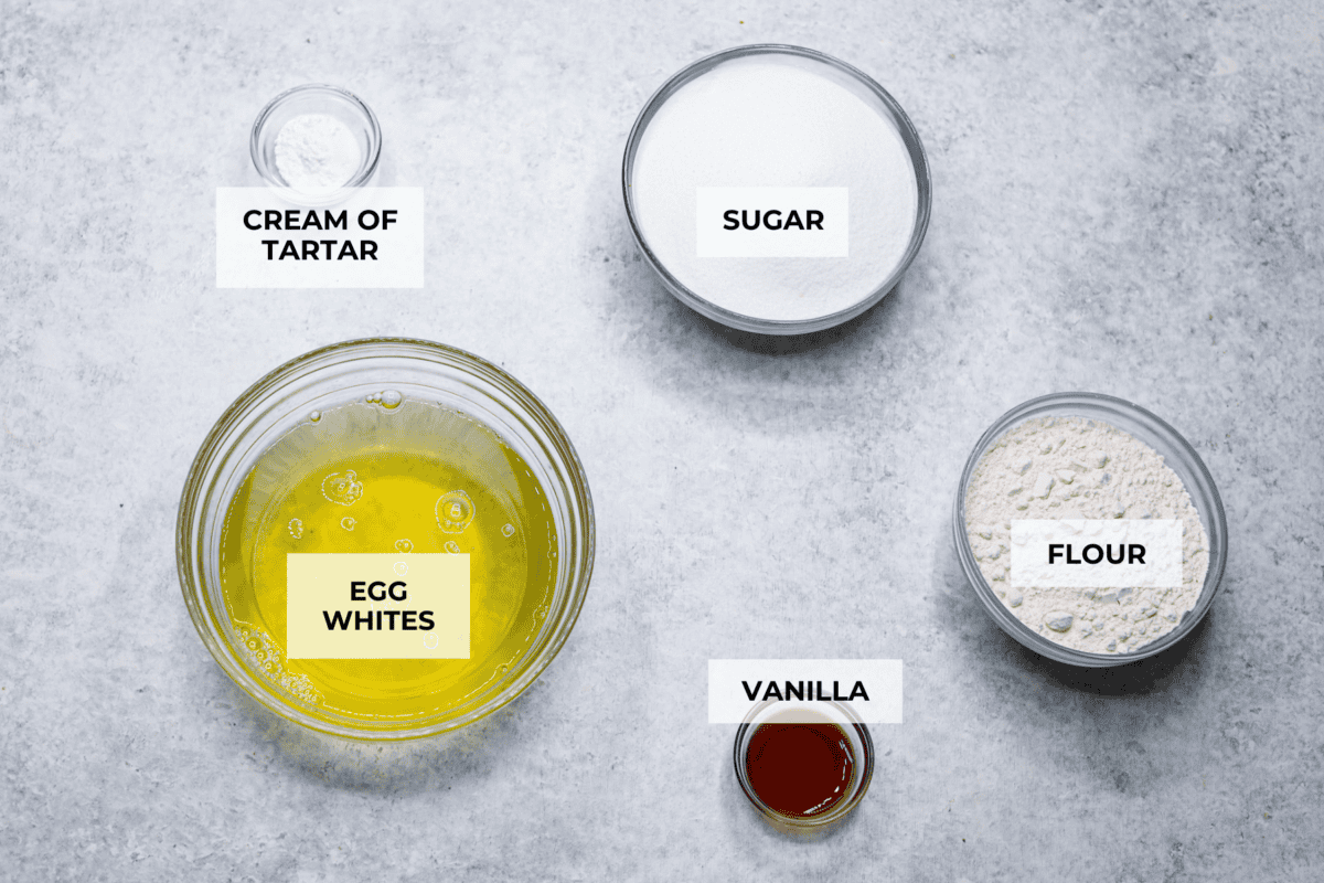 This light & fluffy Angel Food Cake is like a slice of heaven on a plate! It's delicious all on its own but absolutely divine topped with sweetened whipped cream and fresh berries or lemon curd! Overhead shot of labeled ingredients.