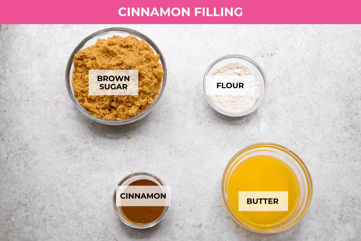 Rich and creamy Cinnamon Roll Cheesecake has the delicious flavor of a cinnamon roll in decadent cheesecake form. This irresistible dessert is made with a cinnamon graham cracker crust, a velvety cream cheese filling with spiced cinnamon throughout, and a classic whipped cream topping. Overhead shot of labeled cinnamon filling ingredients.