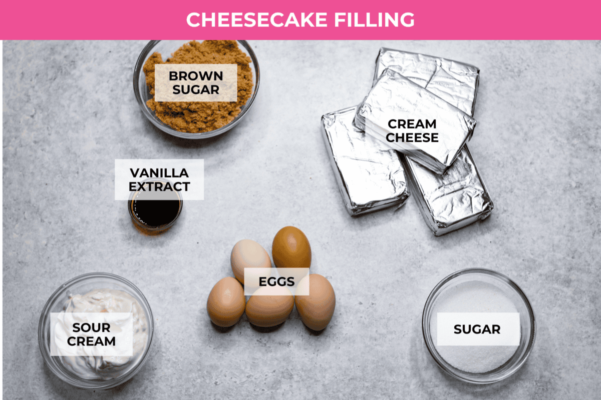 Rich and creamy Cinnamon Roll Cheesecake has the delicious flavor of a cinnamon roll in decadent cheesecake form. This irresistible dessert is made with a cinnamon graham cracker crust, a velvety cream cheese filling with spiced cinnamon throughout, and a classic whipped cream topping. Overhead shot of labeled cheesecake filling ingredients.