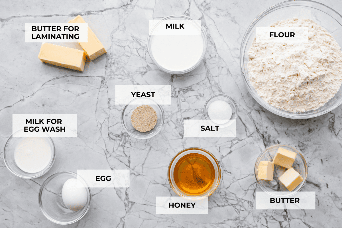 Croissant Bread is beautiful and fluffy with crispy, flaky layers on the outside. It's also one of the most delicious breads you'll ever taste - it will be love at first bite! Add it to your next brunch spread and use it to make French toast, sandwiches, and breakfast casseroles! Overhead shot of labeled ingredients.
