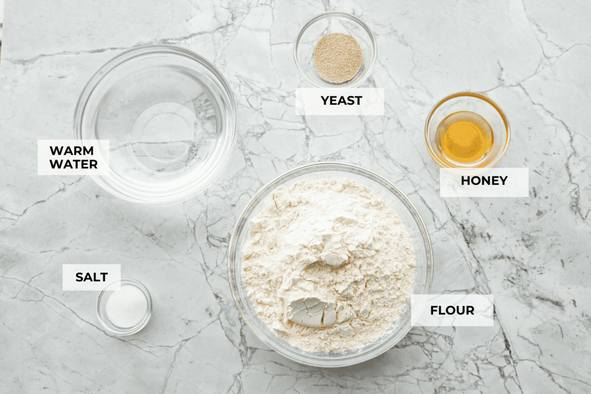 This French baguette recipe is super easy and will change your life! It has a perfect crusty outside and tender, soft inside, perfect for your bread cravings. Overhead shot of labeled ingredients.