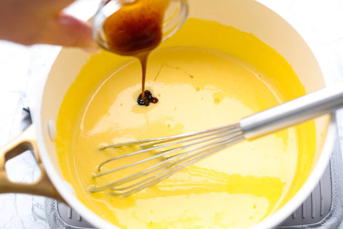 Decadent crème brûlée French toast is fluffy slices of brioche bread with a sweet golden crème brûlée topping. The creme anglaise sauce elevates the French toast making this an unforgettable breakfast! Second photo of the vanilla pouring into the creme anglaise sauce.