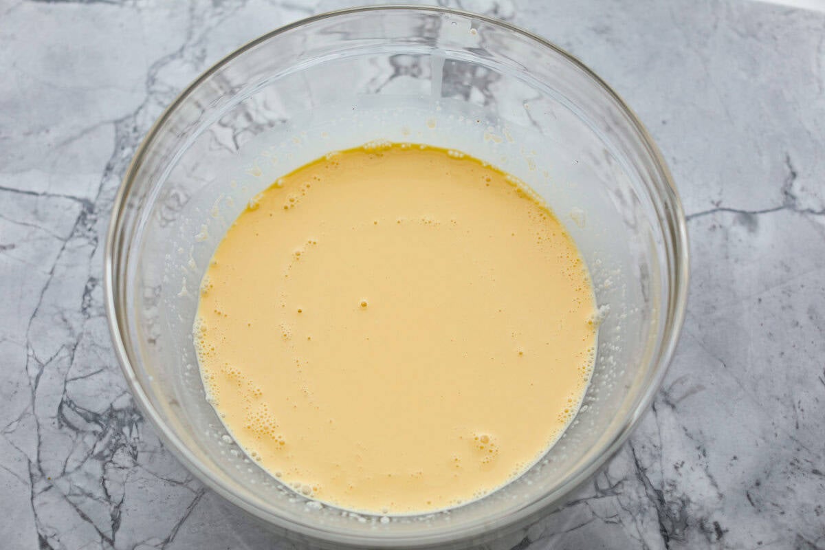 Decadent crème brûlée French toast is fluffy slices of brioche bread with a sweet golden crème brûlée topping. The creme anglaise sauce elevates the French toast making this an unforgettable breakfast! Third photo of the egg mixture mixed in a bowl.