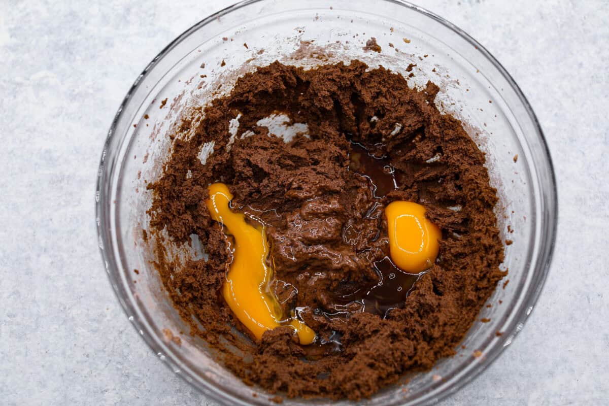 Chocolate Pudding Cookies are soft, chewy, and irresistibly delicious! They are quick and easy to bake and will be a huge hit with anyone who tries them! A glass bowl of cookie dough with eggs added.