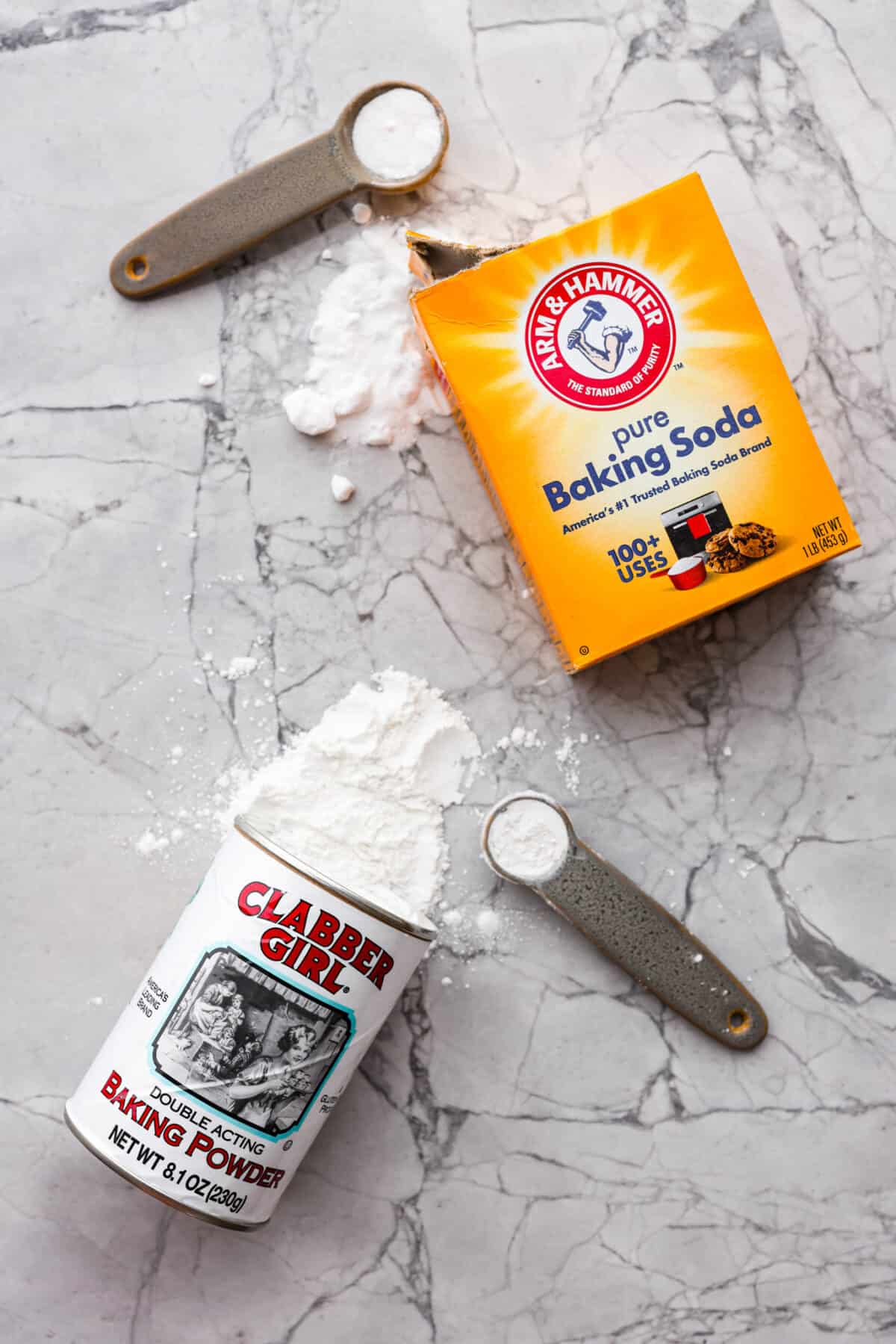 Baking soda vs baking powder....what is the difference? I'm here to teach you the basics of each so that you can improve your baking skills. Learn the whys, hows, and when they're important to achieving delicious recipes. Top view of baking soda and baking powder spilling out of the containers with measuring spoons.