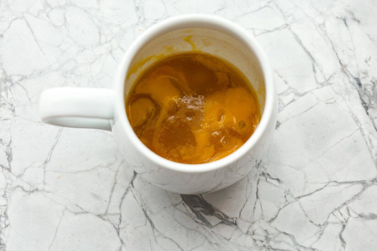 This cookie in a mug recipe is the perfect way to satisfy your cookie craving. In just a few minutes, you can enjoy a warm, buttery, ooey-gooey cookie right in your own mug. Top it with a scoop of ice cream or a dollop of whipped cream, and you'll find yourself in cookie heaven! Overhead shot of sugars, egg yolk and butter mixed in a mug.
