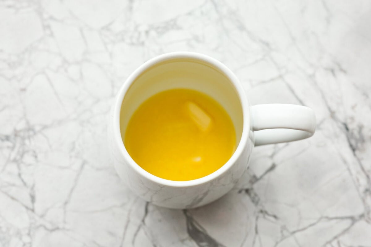 This cookie in a mug recipe is the perfect way to satisfy your cookie craving. In just a few minutes, you can enjoy a warm, buttery, ooey-gooey cookie right in your own mug. Top it with a scoop of ice cream or a dollop of whipped cream, and you'll find yourself in cookie heaven! Overhead shot of butter melted in a mug.