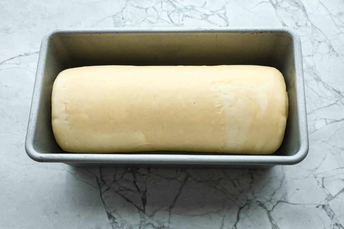 Croissant Bread is beautiful and fluffy with crispy, flaky layers on the outside. It's also one of the most delicious breads you'll ever taste - it will be love at first bite! Add it to your next brunch spread and use it to make French toast, sandwiches, and breakfast casseroles! Overhead shot of rolled dough in loaf pan.