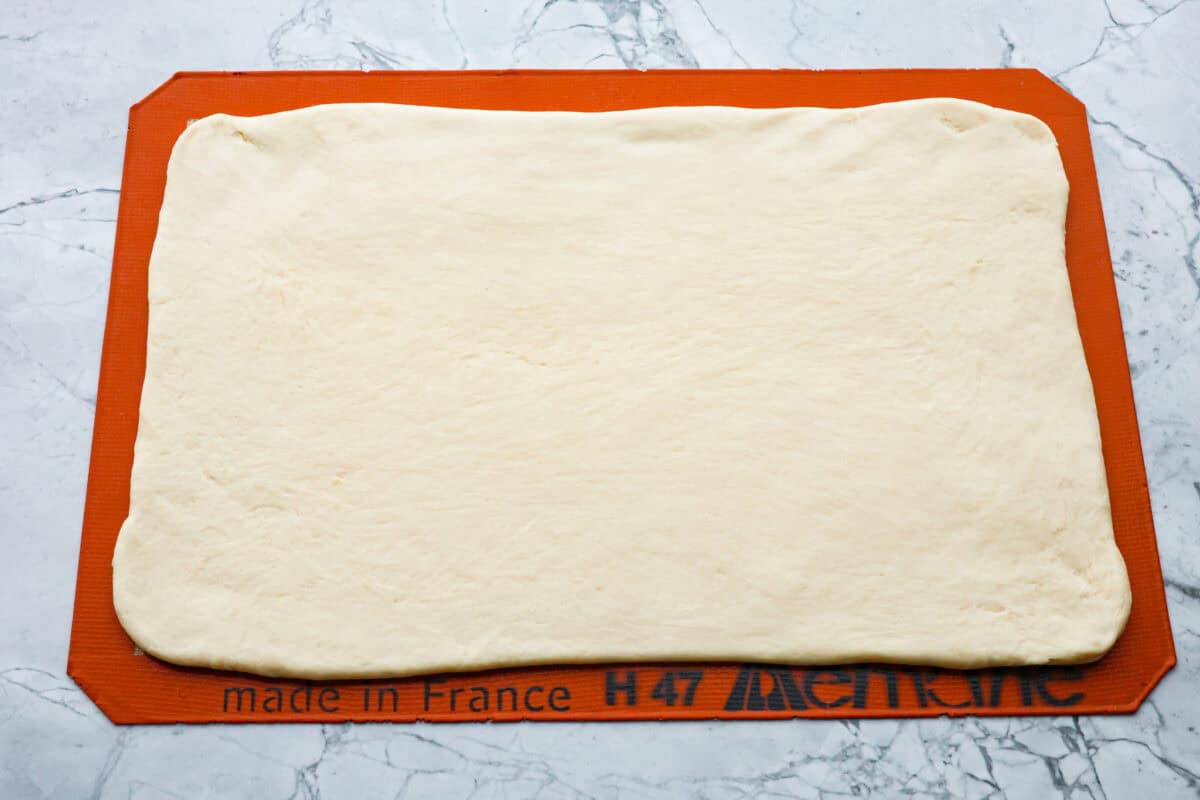 Croissant Bread is beautiful and fluffy with crispy, flaky layers on the outside. It's also one of the most delicious breads you'll ever taste - it will be love at first bite! Add it to your next brunch spread and use it to make French toast, sandwiches, and breakfast casseroles! Overhead shot of dough pounded out into a 9x14 rectangle.
