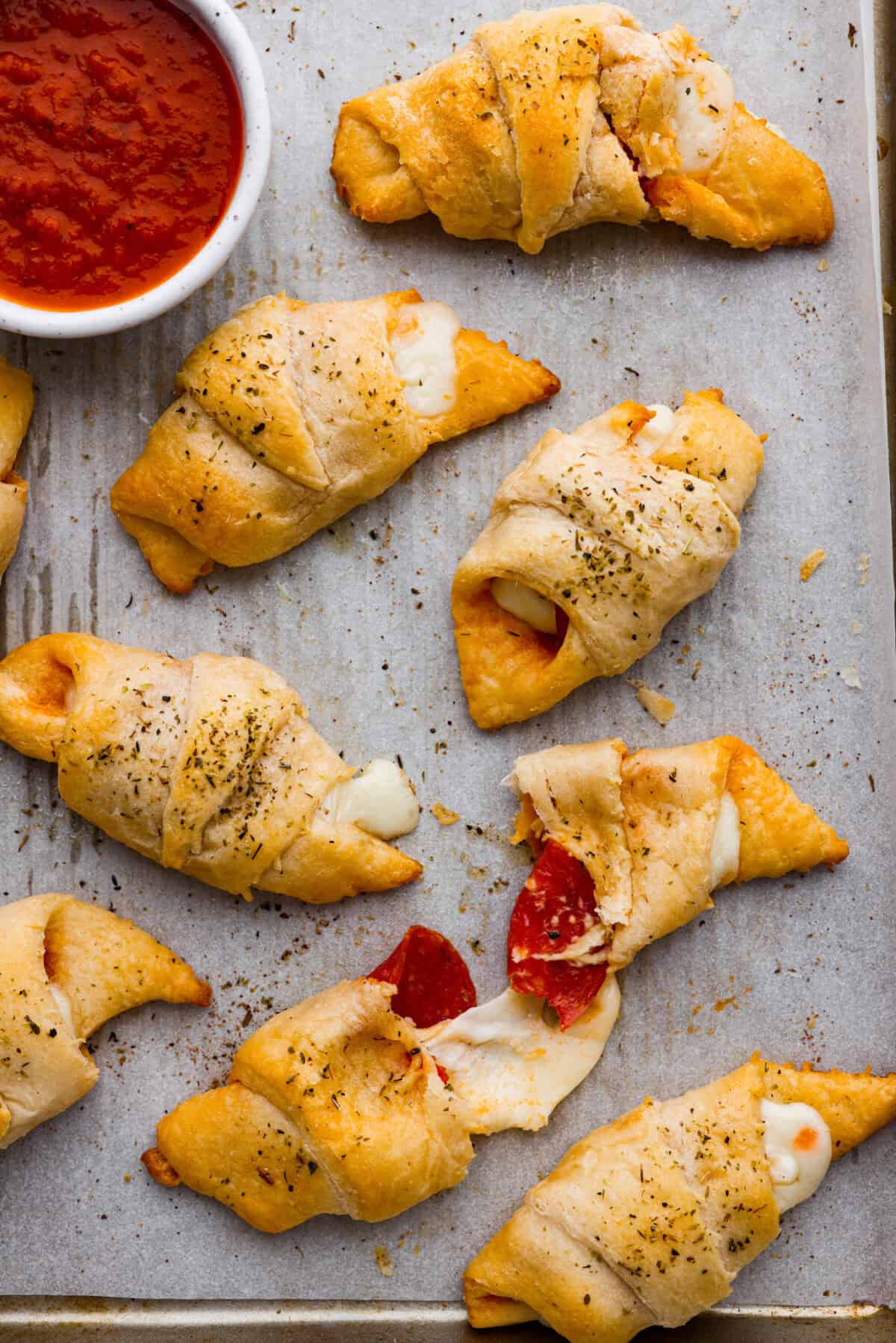Pizza Stuffed Crescent Rolls areย loaded with gooey mozzarella cheese and pepperoni. Serve with warm marinara for dipping! Overhead shot of a pan of pizza stuffed crescent rolls with gooey cheese melting out of the edges.