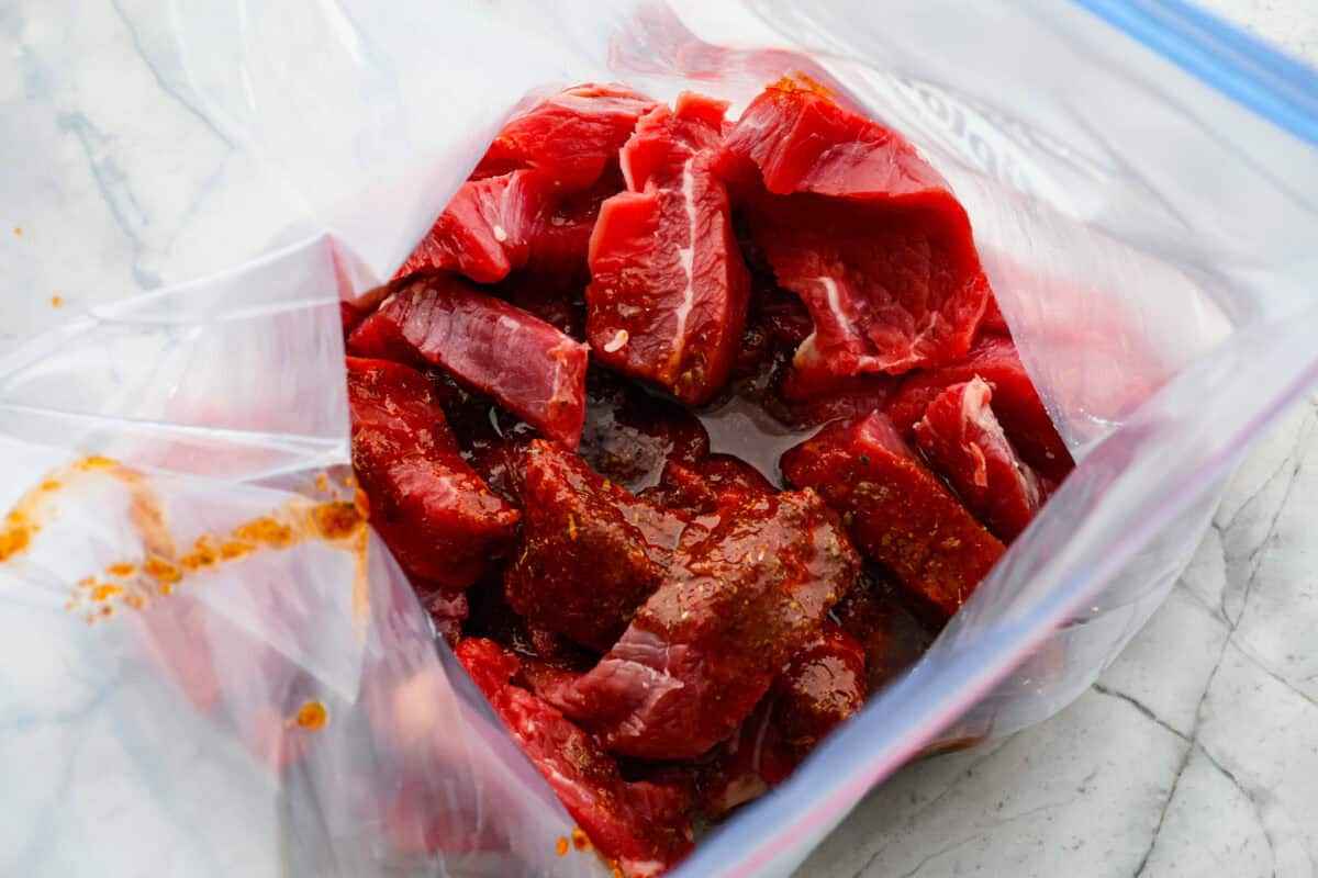 Sheet pan steak fajitas are beautiful and bursting with flavor. Easy to throw together on busy weeknights, they feature tender steak and crisp, colorful vegetables in every bite. You will definitely want to add this to your weekly meal planning! Overhead shot of sliced meat in bag with marinade poured over it.