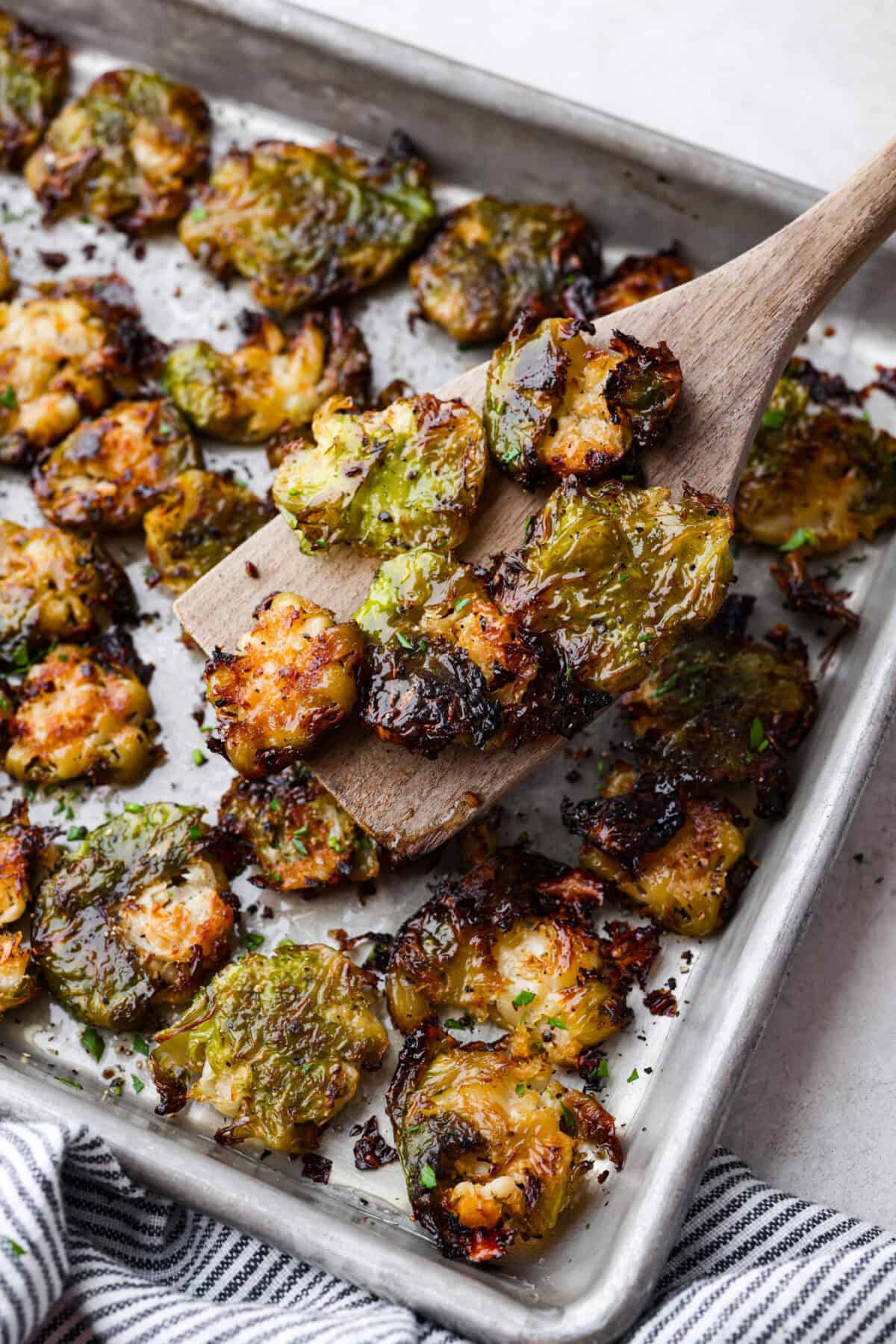 Irresistibly crispy Smashed Brussels Sprouts areย simple to make, loaded with delicious flavor, and have the best crunchy texture. These pair well with almost any protein and will definitely upgrade your side dish game! Angle shot of a wooden spatula holding up a few smashed Brussels sprouts out of the pan.