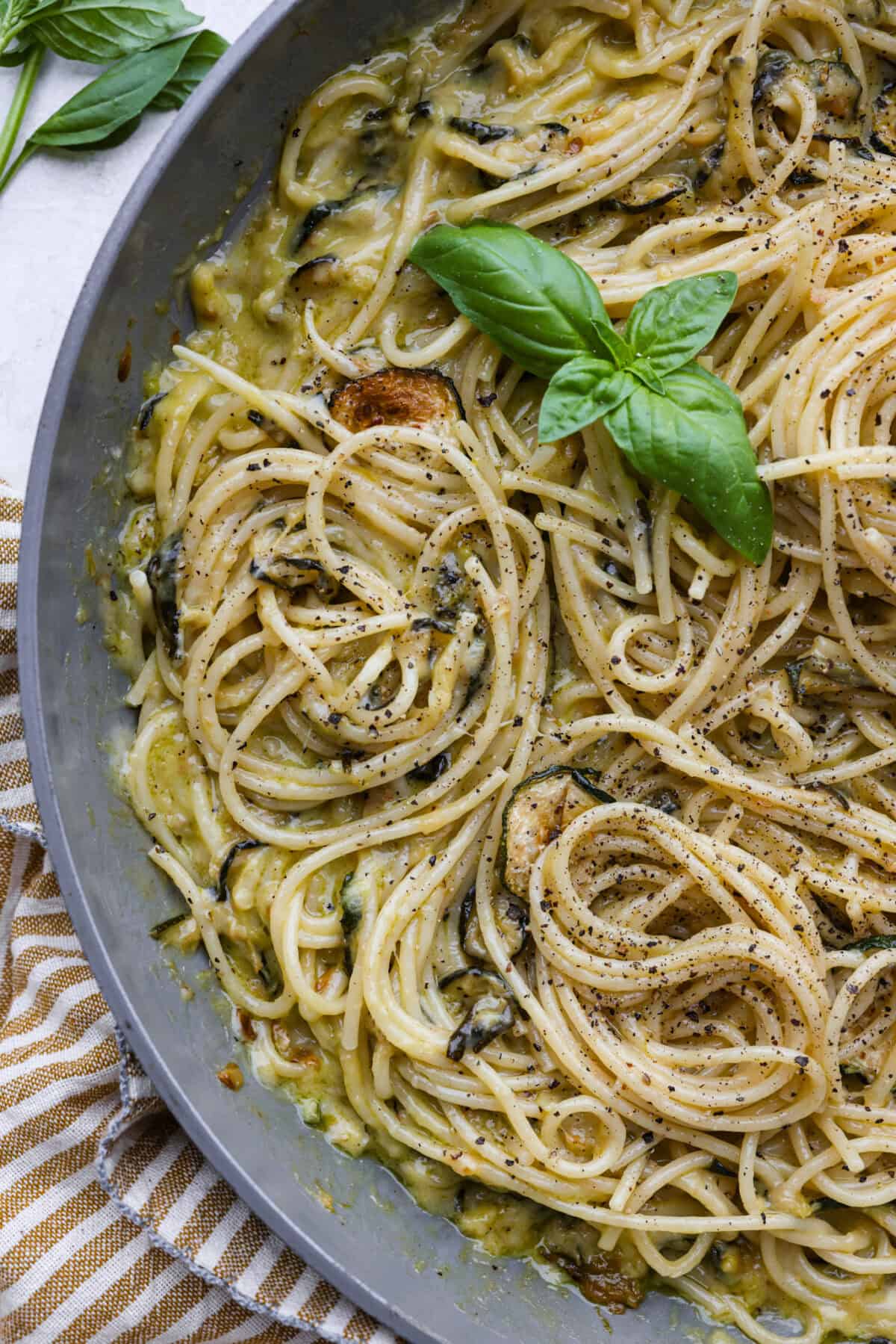 Spaghetti alla Nerano is an unforgettable pasta dish packed with flavor! It has a rich and creamy zucchini sauce infused with garlic, fresh basil, and melted cheese. Close view of the spaghetti alla Nerano in a skillet garnished with fresh basil leaves.
