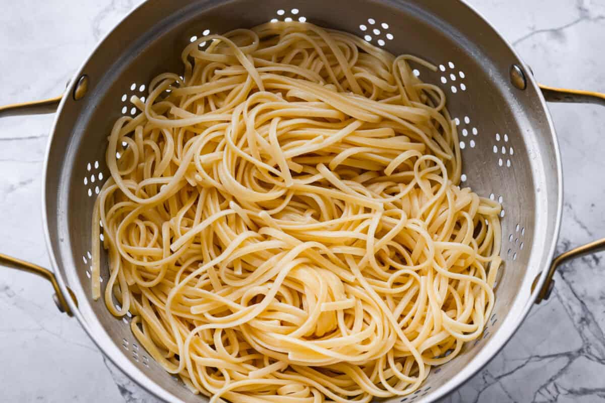 Packed with flavor, these easy Teriyaki Noodles are so much better than takeout! Throw these together in just 20 minutes with pantry staples for the perfect busy weeknight dinner. You can keep it vegetarian or serve it alongside your favorite protein. Overhead shot of cooked and drained noodles in a colander.