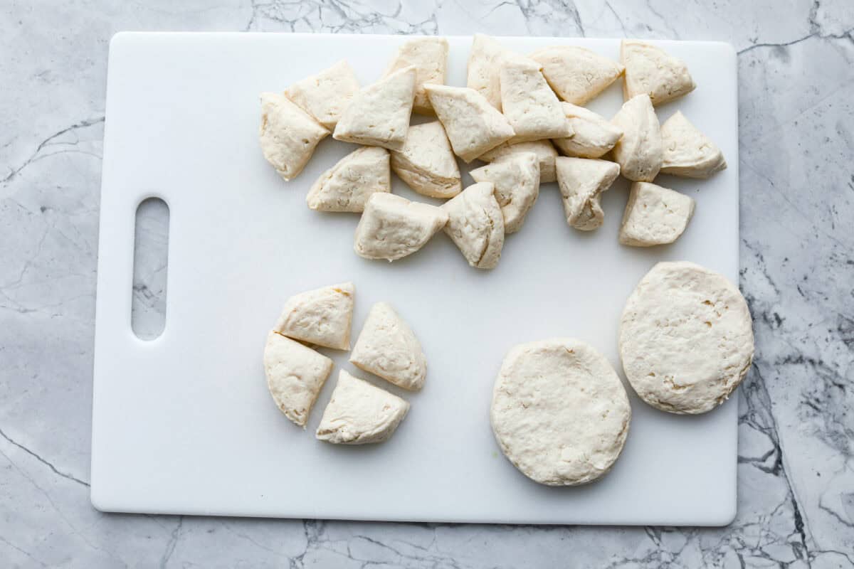 Rise and shine to Breakfast Monkey Bread with delicious savory flavors! It’s made with Grands biscuits, eggs, sausage, bacon, and cheese, all baked in a bundt pan. The result is crowd-pleasing pull-apart bread that everyone will devour! Overhead shot o cut up biscuits on cutting board.