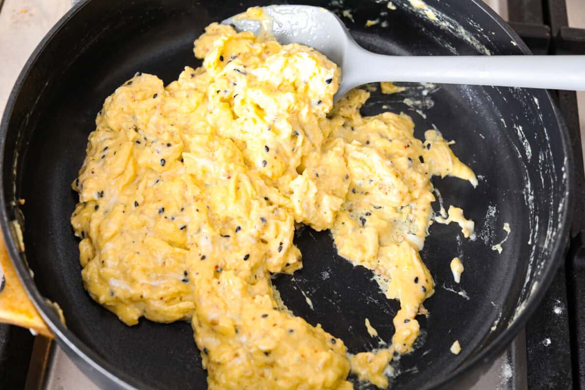 Rise and shine to Breakfast Monkey Bread with delicious savory flavors! It’s made with Grands biscuits, eggs, sausage, bacon, and cheese, all baked in a bundt pan. The result is crowd-pleasing pull-apart bread that everyone will devour! Overhead shot of egg mixture being scrambled in a pan.