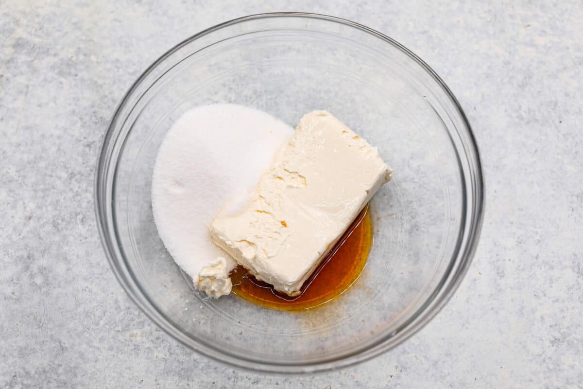 Enjoy juicy, ripe peaches in this Fresh Peach Pie. It has a creamy cheesecake filling topped with sweet peaches, all nestled in a buttery graham cracker crust. Itโs simply delightful, and no baking is required! Overhead shot of sugar, cream cheese and vanilla in a glass bowl.