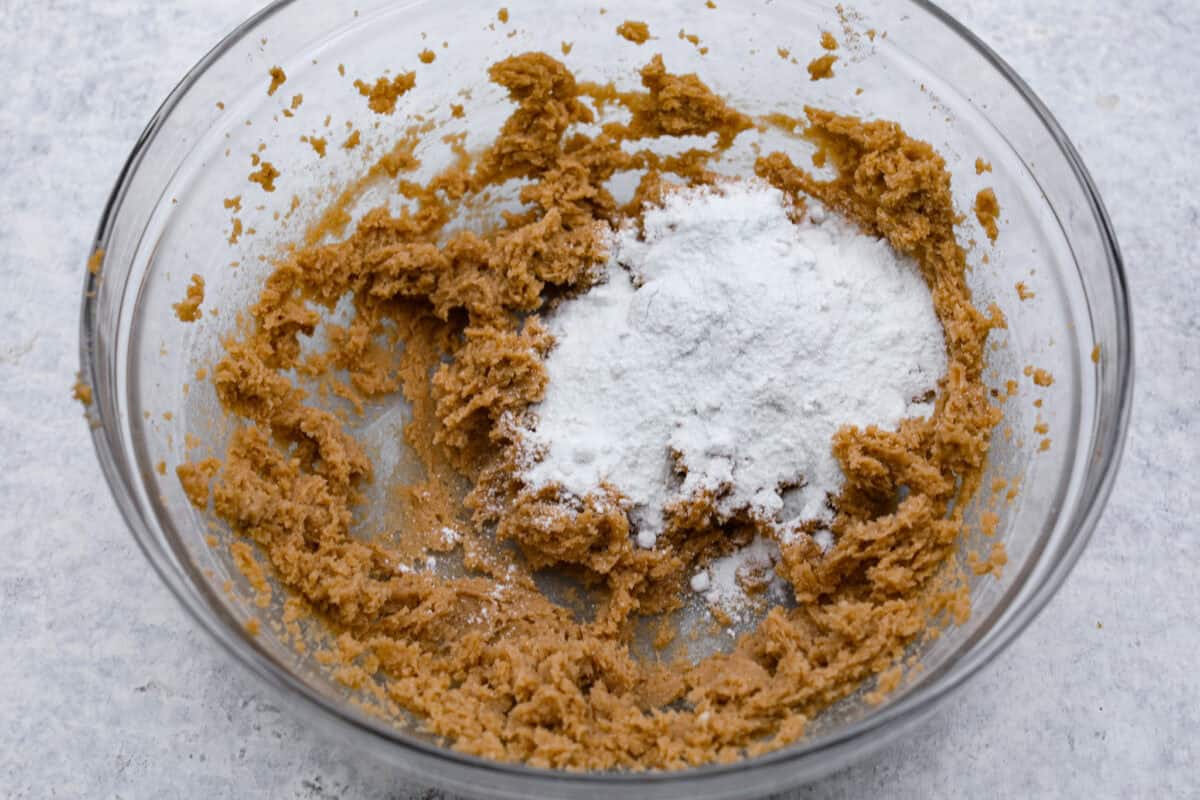 Pistachio Pudding Cookies are super soft, chewy, and irresistible! They're easy to make, and adding pistachio pudding mix gives this cookie recipe wonderful flavor and the perfect tender texture! Overhead shot of beat butter and sugars with pudding mix on top.