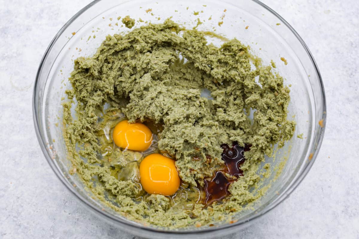 Pistachio Pudding Cookies are super soft, chewy, and irresistible! They're easy to make, and adding pistachio pudding mix gives this cookie recipe wonderful flavor and the perfect tender texture! Overhead shot of the butter, sugar and pudding mixture with eggs and extracts.