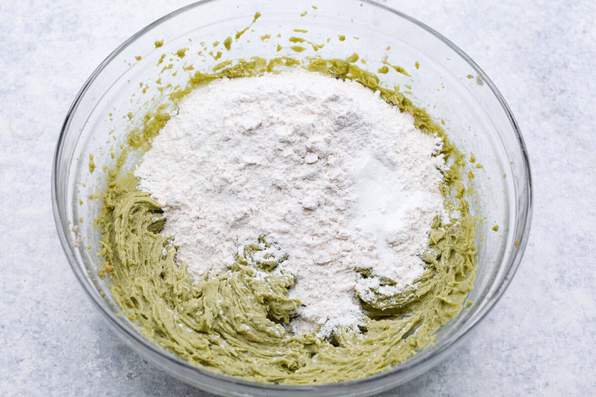 Pistachio Pudding Cookies are super soft, chewy, and irresistible! They're easy to make, and adding pistachio pudding mix gives this cookie recipe wonderful flavor and the perfect tender texture! Overhead shot of the dry ingredients on top of the cookie dough.