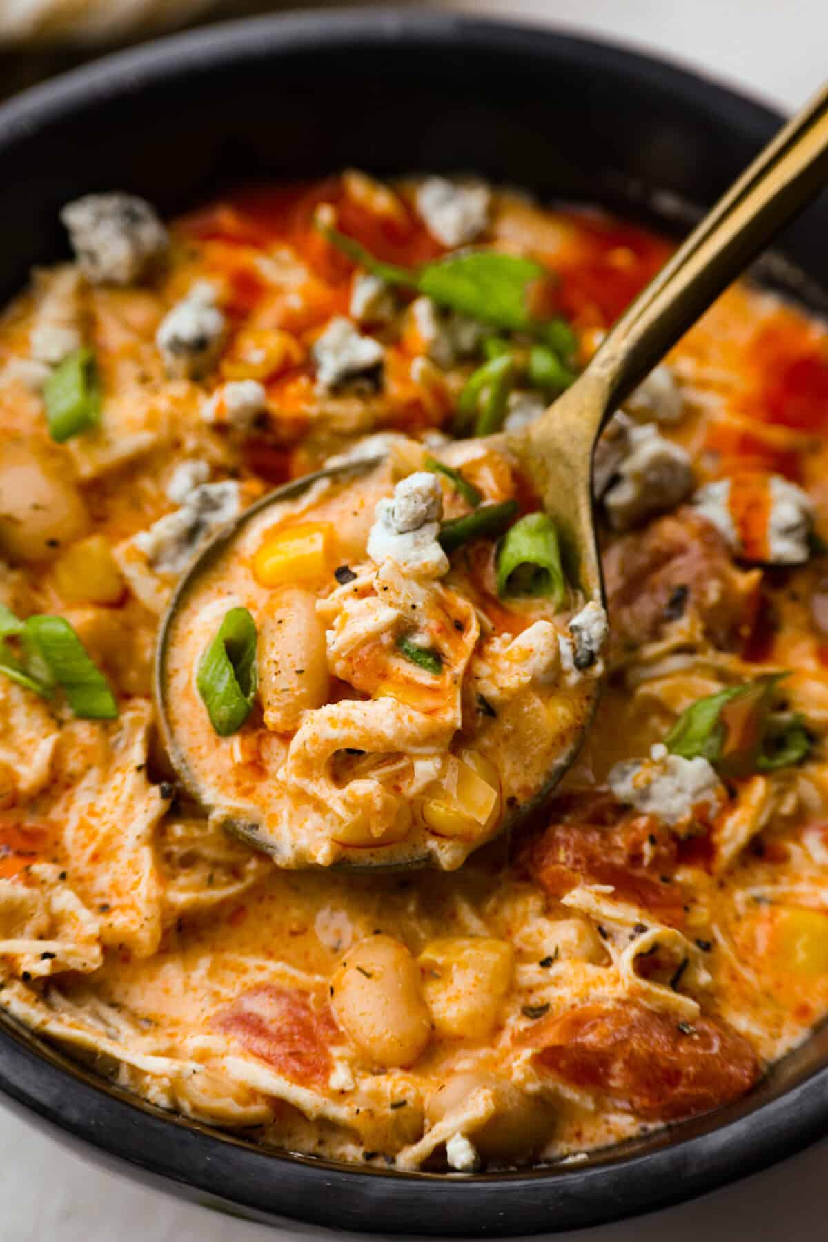 Crockpot buffalo chicken chili is a buffalo wing lover's dream. It has a tangy, fiery buffalo hot sauce base mixed with shredded chicken, smooth cream cheese, tender beans, and vegetables. If you love buffalo wings, you will love this chili! Close up shot of crockpot buffalo chicken chili.
