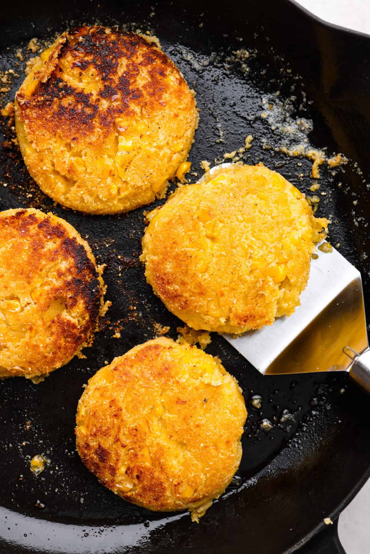 Homemade Sweet Corn Tamale Cakes are an explosion of delicious flavor in every bite! With this easy recipe you can bring this Cheesecake Factory favorite right to your own kitchen. Add the signature topping to really take these to the next level! Close up should of corn cakes frying in skillet.