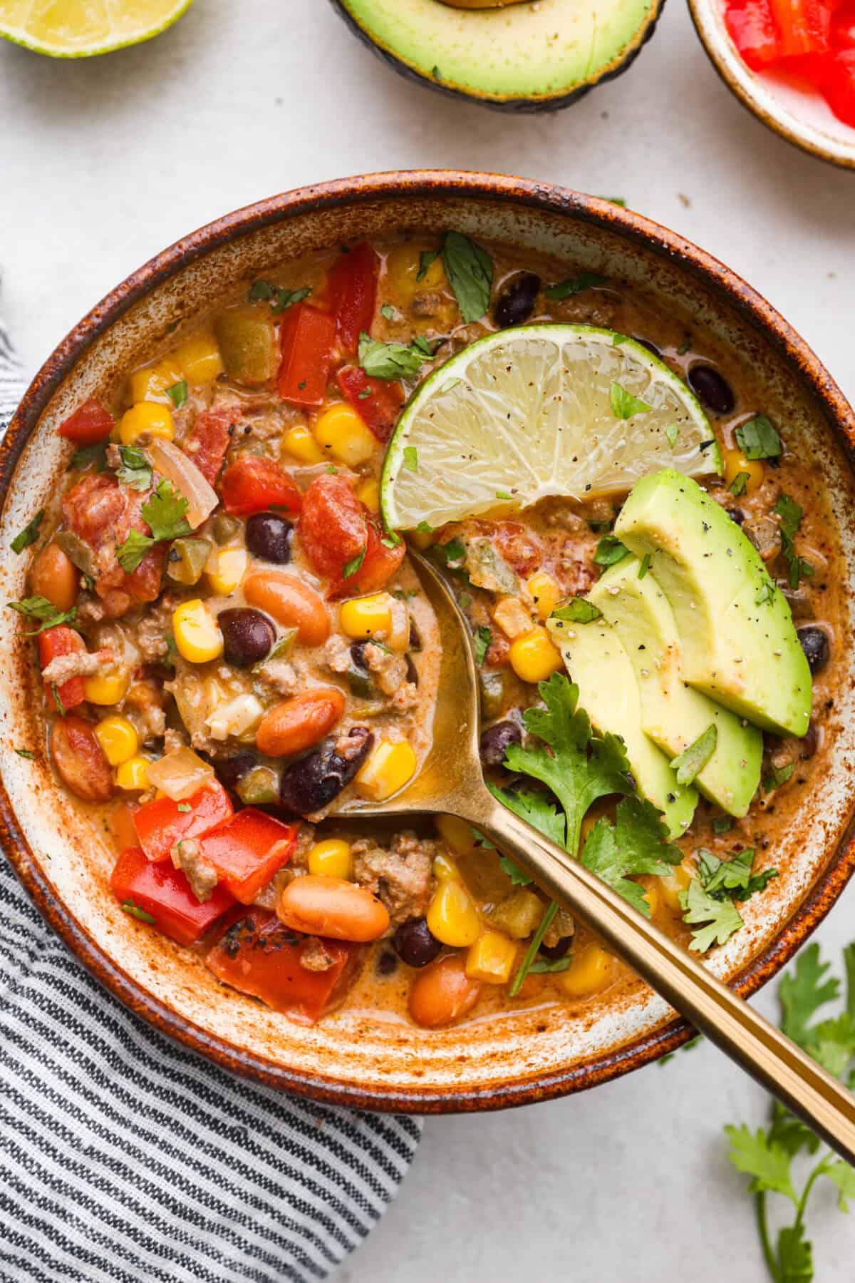 This creamy taco soup recipe is full of fresh flavors, tender vegetables, and hearty beans. The seasoned beef mixed with the creamy soup is out of this world good! Top it with your favorite toppings, and your family will love this warm, savory soup! Overhead shot of a bowl of creamy taco soup.