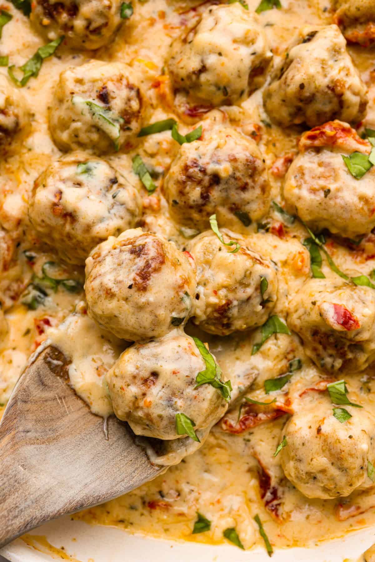With creamy Tuscan flavors, these Marry Me Meatballs are an instant crowd favorite! It doesn't get much better than Italian seasoned chicken meatballs nestled in a creamy, cheesy sauce with sun-dried tomatoes and fresh herbs. Close up shot of marry me meatballs.