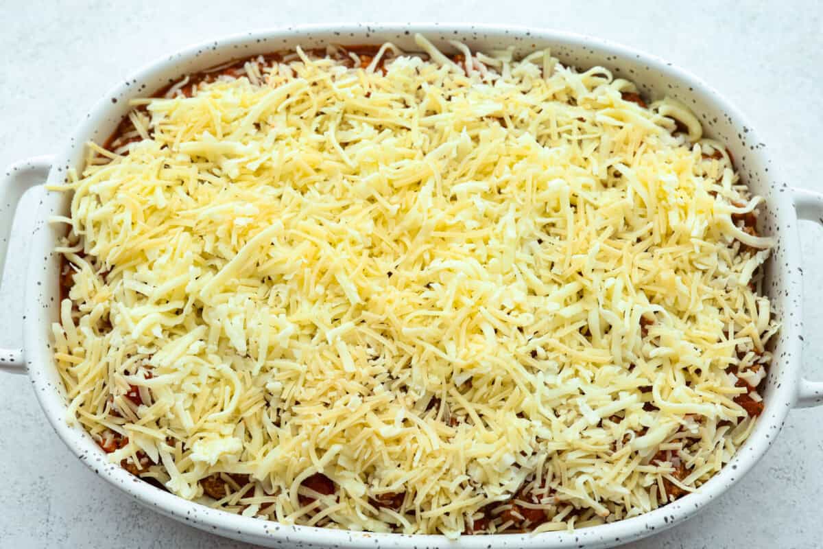 Million Dollar Ravioli Casseroleย is a flavorful casserole version of the classic! It's easy to make with mouthwatering layers of cheesy ravioli, meat sauce, and melted mozzarella cheese on top. This is a comforting, family-friendly dinner that you'll be craving on repeat! Overhead shot of the ravioli and cheese with meat and sauce mixture topped with cheese.