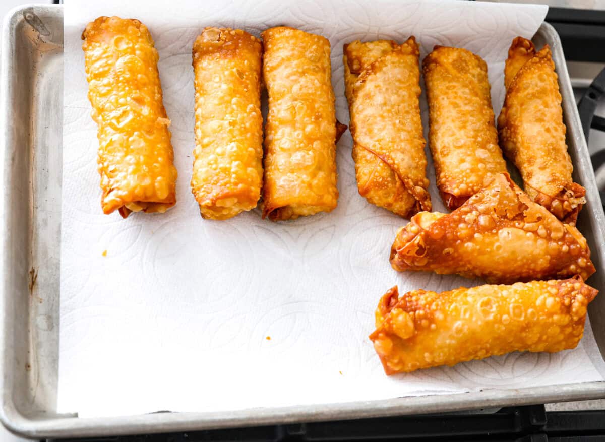Crispy outside with a warm, flavorful filling, these Shrimp Egg Rolls are beyond delicious! They're packed with a mix of vermicelli noodles, sautéed veggies, shrimp and plenty of flavorings, then fried till crunchy and golden brown. Serve them as an appetizer, a light main or party side dish! Overhead shot of fried shrimp egg rolls cooling on a baking sheet with parchment paper.