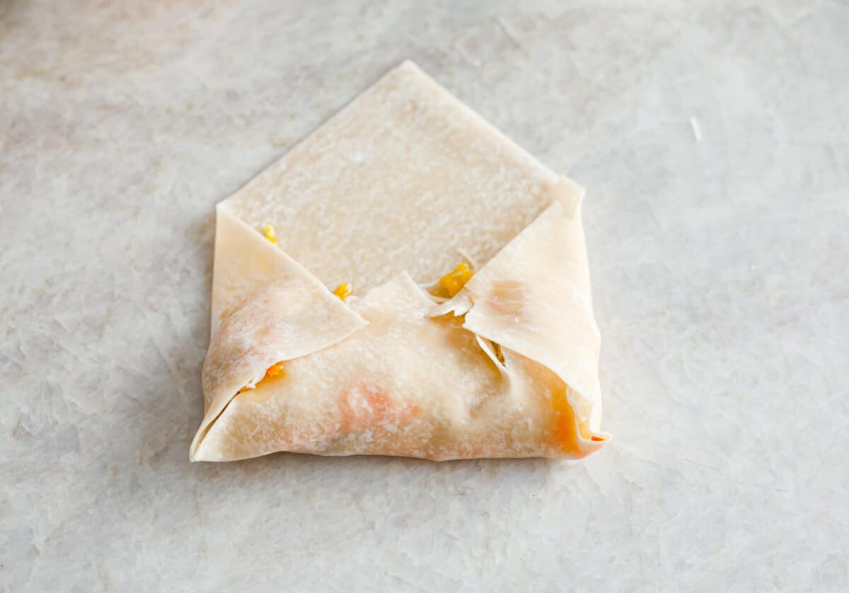 Crispy outside with a warm, flavorful filling, these Shrimp Egg Rolls are beyond delicious! They're packed with a mix of vermicelli noodles, sautéed veggies, shrimp and plenty of flavorings, then fried till crunchy and golden brown. Serve them as an appetizer, a light main or party side dish! Overhead shot of shrimp egg roll being wrapped in wrapping.