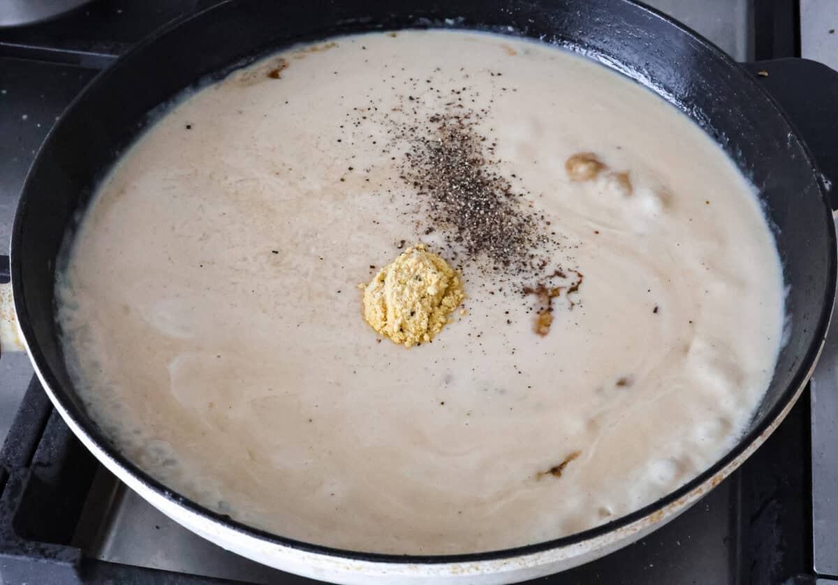 Smothered chicken is a flavorful comfort food full of rich, creamy gravy, tender chicken cutlets, and savory mushrooms. Perfect on its own or paired with mashed potatoes, rice or pasta, you're family will definitely want this on the weekly meal plan. Overhead hot of cream and seasonings in the skillet.