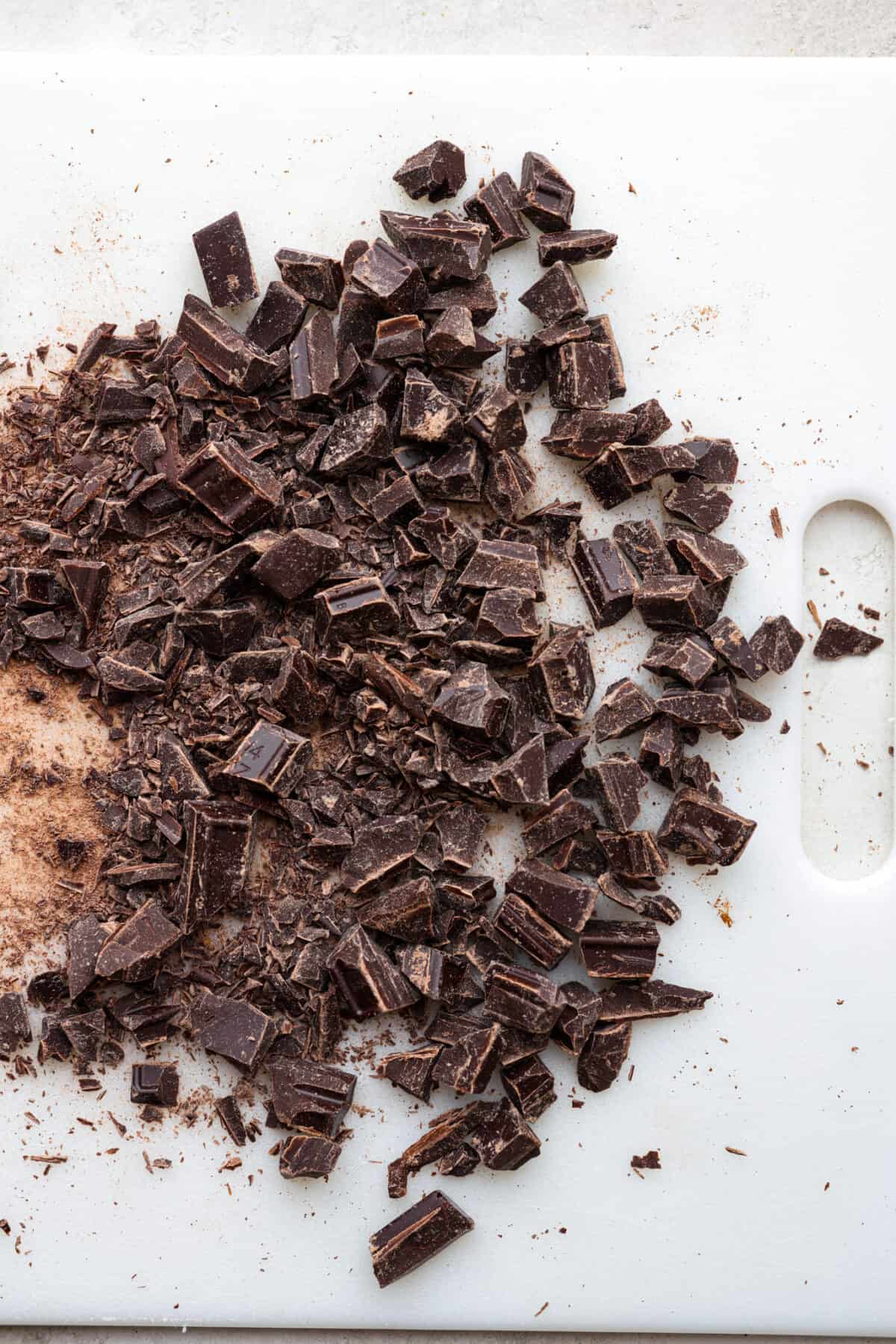 Learn how to temper chocolate for all your chocolate dipping and candy-making needs! Tempering chocolate can be intimidating but my how-to guide will help you every step of the way. Top view of chopped chocolate on a cutting board.