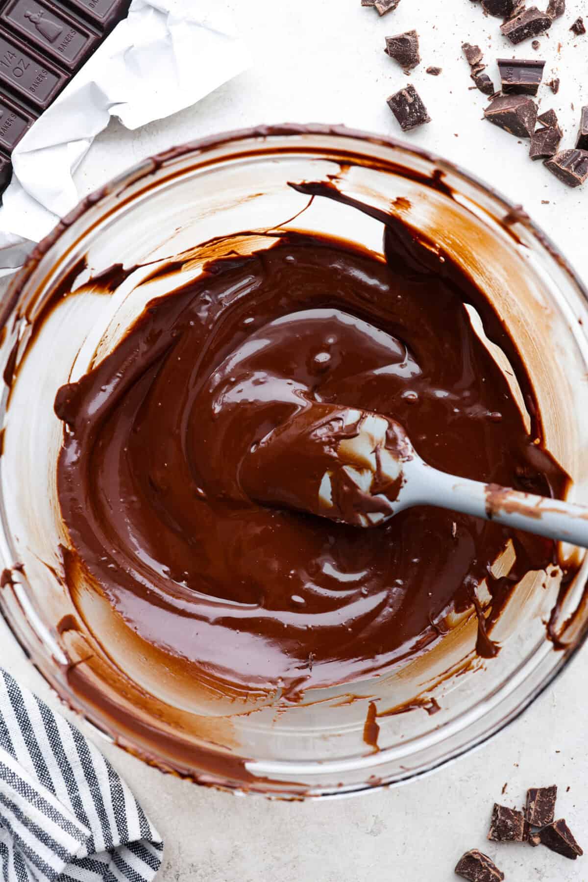 Learn how to temper chocolate for all your chocolate dipping and candy-making needs! Tempering chocolate can be intimidating but my how-to guide will help you every step of the way. Top view of tempered chocolate in a glass bowl with a spatula.