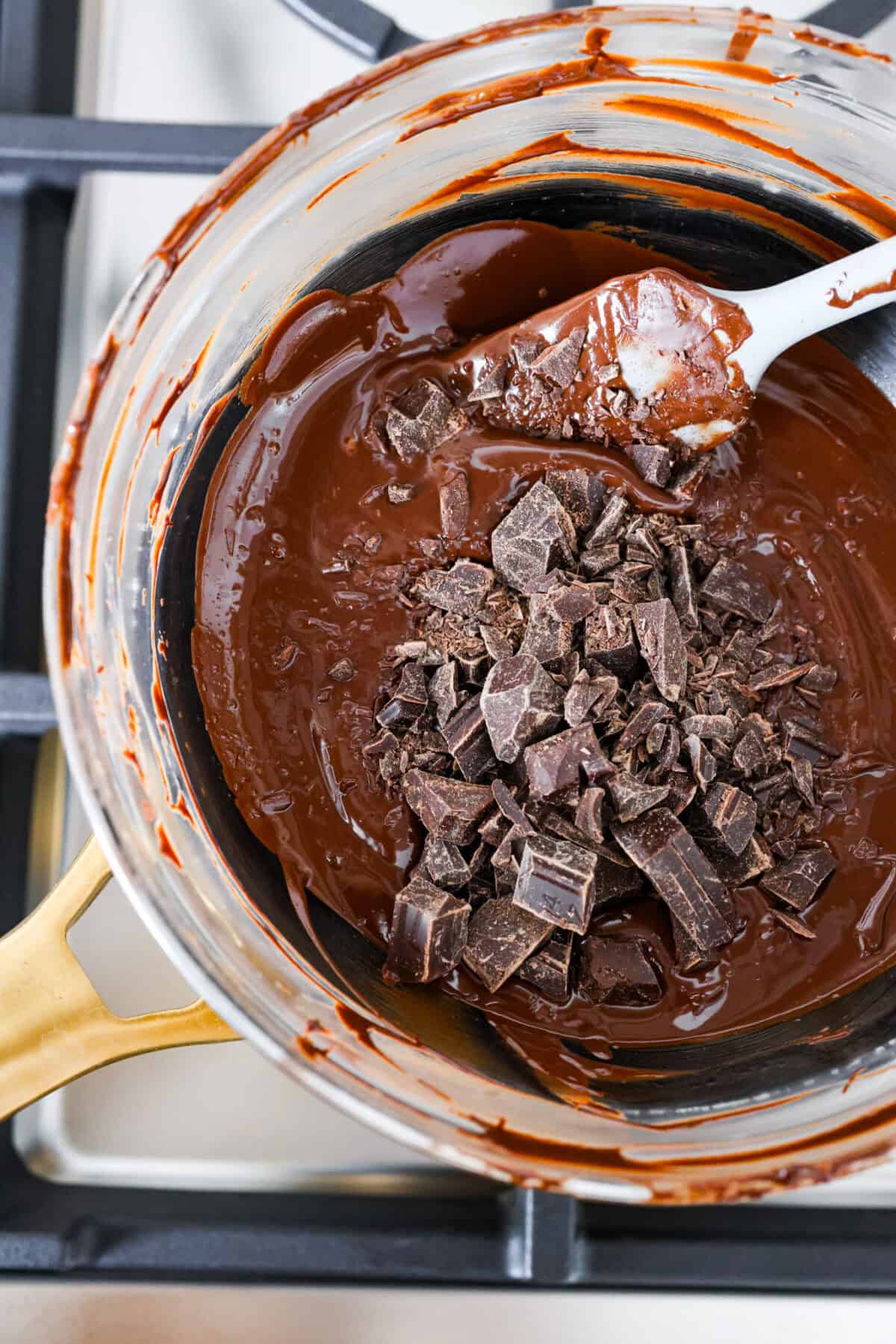 Learn how to temper chocolate for all your chocolate dipping and candy-making needs! Tempering chocolate can be intimidating but my how-to guide will help you every step of the way. Top close view of melted chocolate in a bowl with chopped chocolate added on top for seeding.