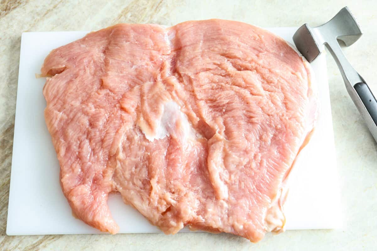 Make Turkey Roulade your new Thanksgiving tradition! Boneless turkey breast gets flattened and rolled with sausage stuffing inside. The turkey turns out incredibly moist and is infused with your favorite Thanksgiving flavors. It takes far less time than traditional turkey and will make Thanksgiving day easy and delicious! First photo of the turkey breast butterflied and flattened.