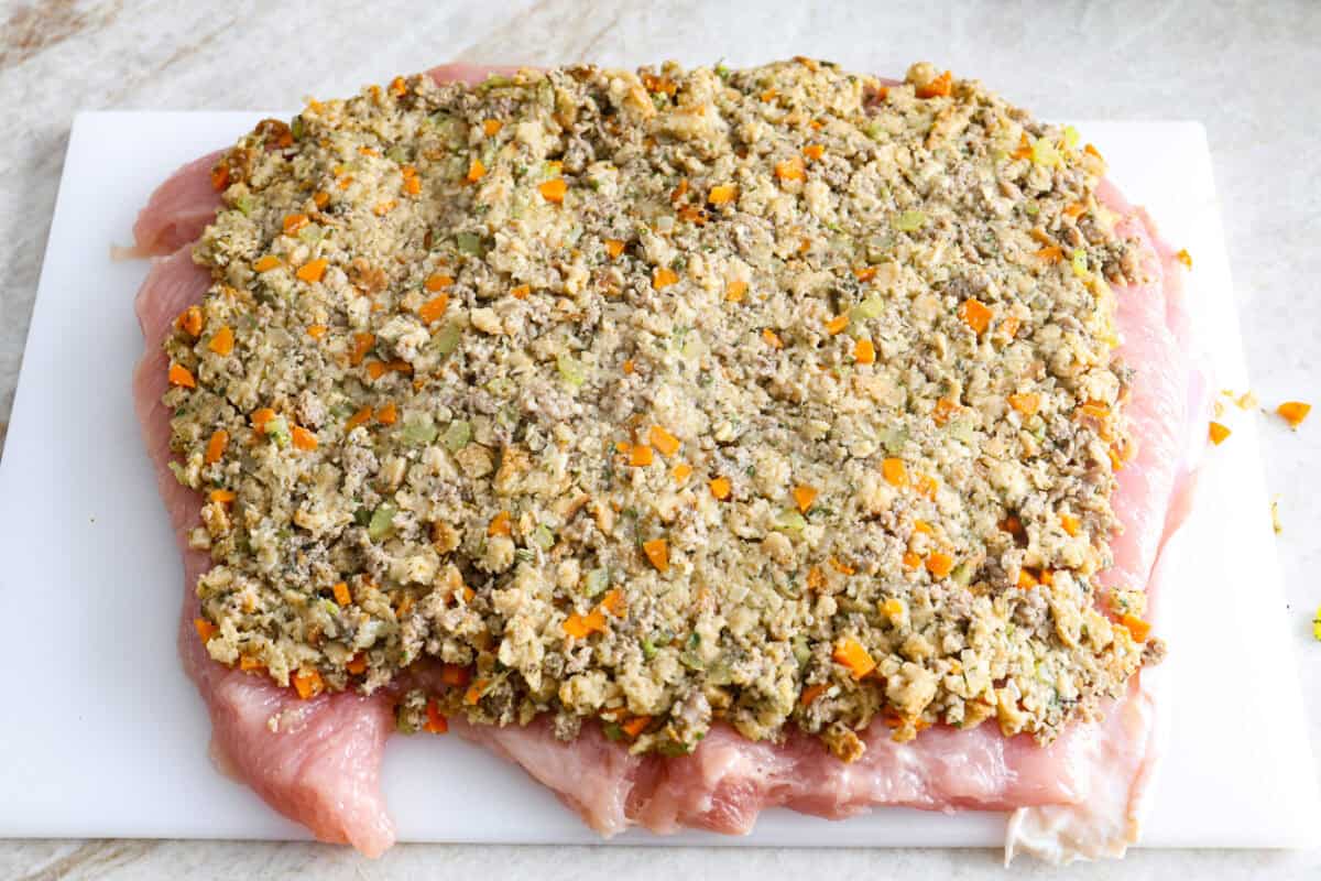 Make Turkey Roulade your new Thanksgiving tradition! Boneless turkey breast gets flattened and rolled with sausage stuffing inside. The turkey turns out incredibly moist and is infused with your favorite Thanksgiving flavors. It takes far less time than traditional turkey and will make Thanksgiving day easy and delicious! Fifth photo of the stuffing spread on the flattened turkey breast.