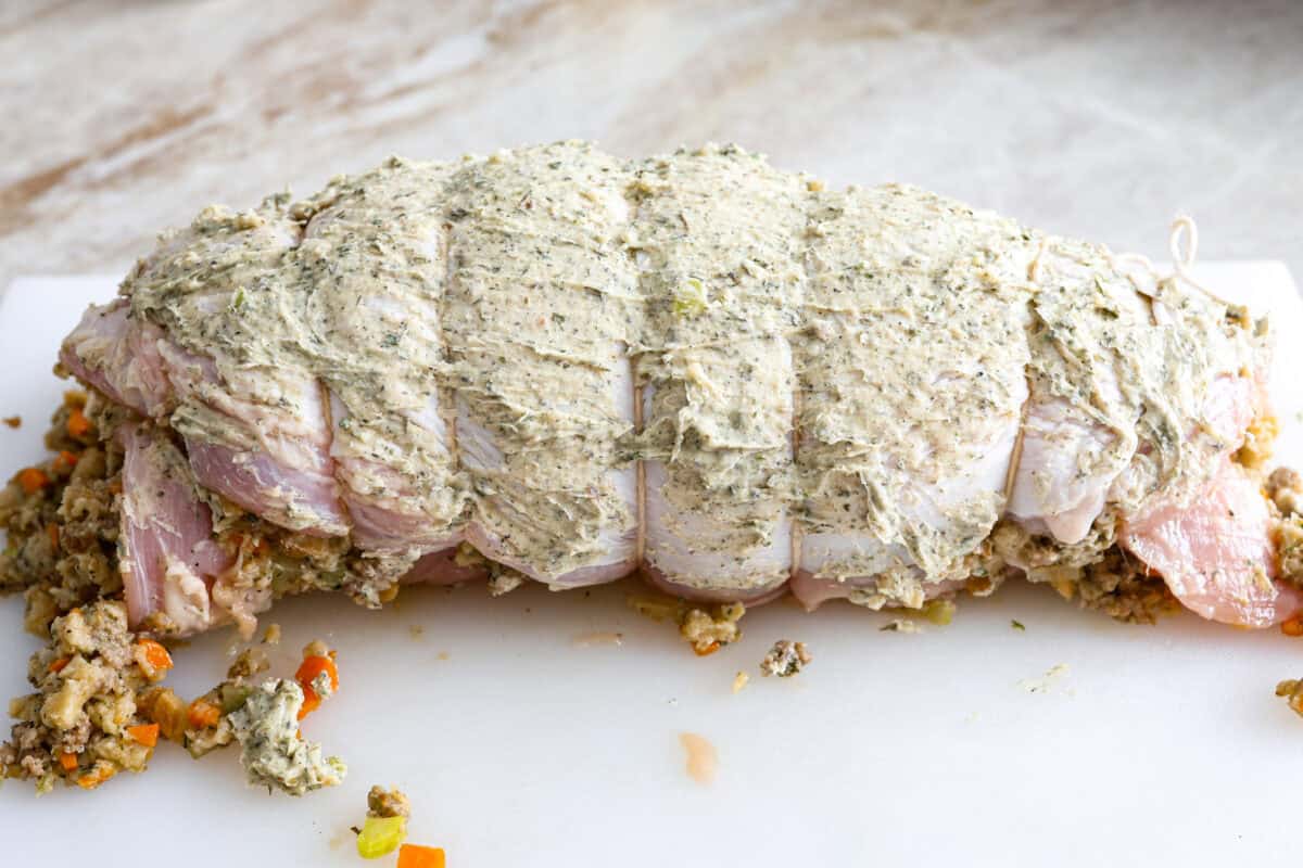 Make Turkey Roulade your new Thanksgiving tradition! Boneless turkey breast gets flattened and rolled with sausage stuffing inside. The turkey turns out incredibly moist and is infused with your favorite Thanksgiving flavors. It takes far less time than traditional turkey and will make Thanksgiving day easy and delicious! Sixth photo of the turkey roulade rolled, buttered, and tied.