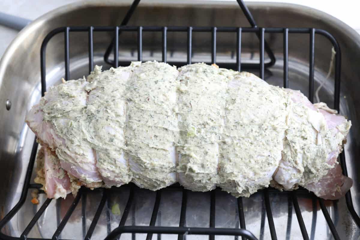 Make Turkey Roulade your new Thanksgiving tradition! Boneless turkey breast gets flattened and rolled with sausage stuffing inside. The turkey turns out incredibly moist and is infused with your favorite Thanksgiving flavors. It takes far less time than traditional turkey and will make Thanksgiving day easy and delicious! Seventh photo of the turkey roulade in a roasting pan to bake.