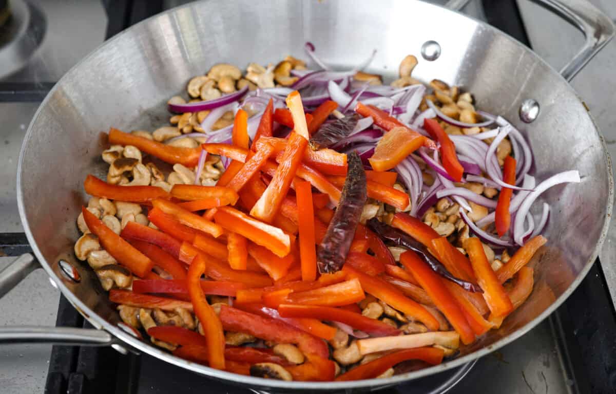 Dragon Chicken is a spicy and flavorful dish featuring tender breaded chicken stir-fried with vegetables and coated in a rich, tangy, and slightly sweet sauce. It's a crowd favorite for those who enjoy a fiery twist on the classic stir-fry! Angle shot of stir fry ingredients in a wok.