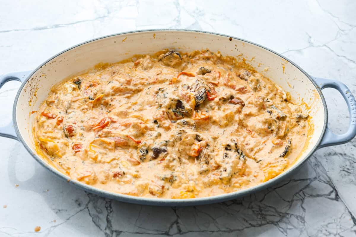 This Boursin pasta recipe has gone viral on social media. It's simple to make and packed with flavor! It's creamy with a distinct zingy bite from the Boursin cheese and sundried tomatoes. This dish screams flavor! It's anything but boring. Angle shot of sauce in a skillet.