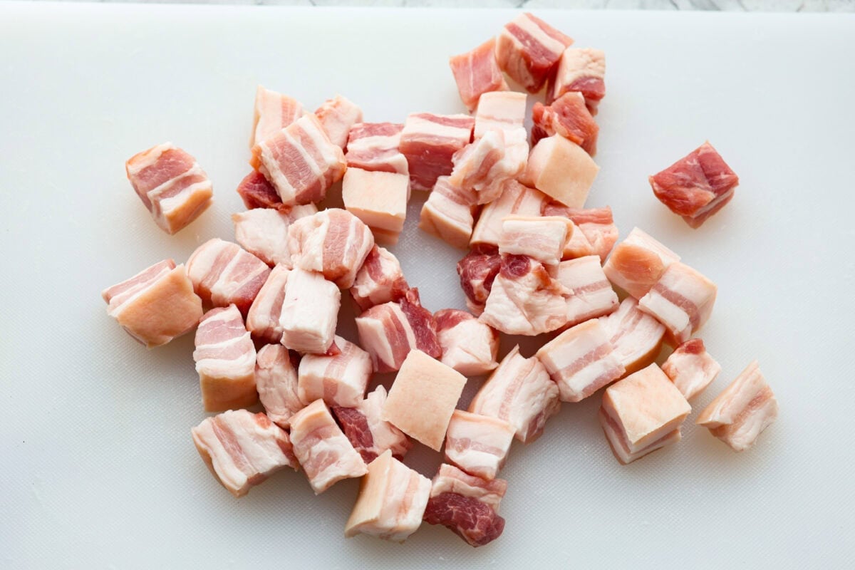 This simple air fryer pork belly recipe is great for making and enjoying this indulgent snack. It's meaty, crispy, smothered in a sticky, salty marinade that sets the flavors off perfectly! Overhead shot of pork belly cut into 1 inch pieces.