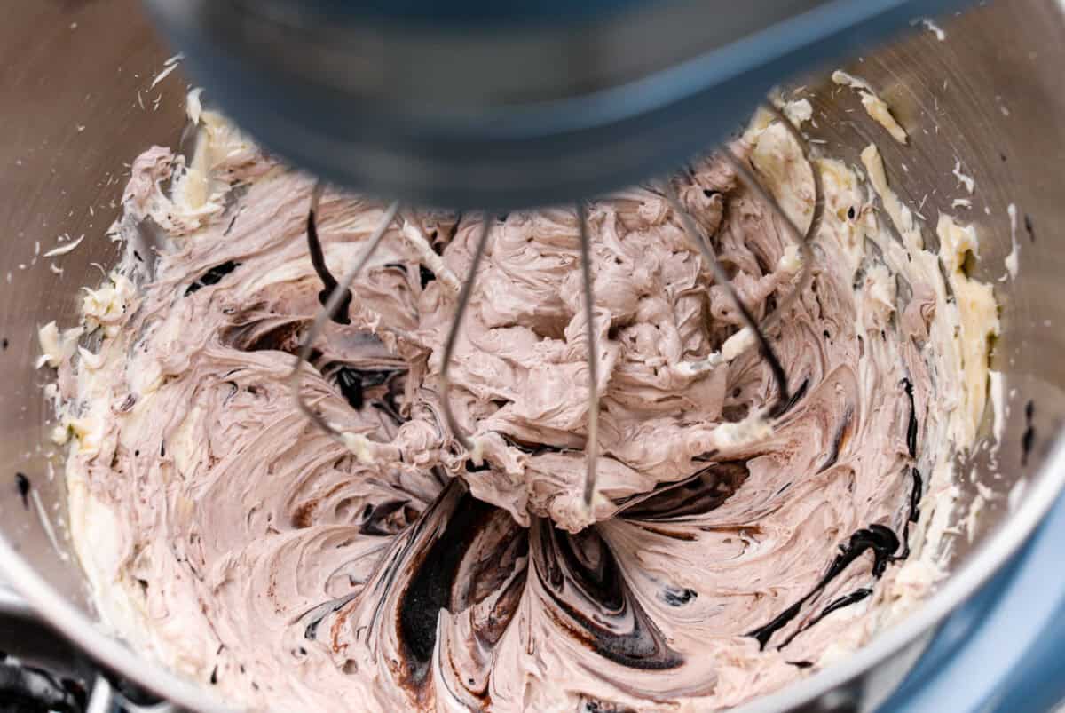 This delicious black frosting is fun to make for special occasions, especially for Halloween, seasonal treats, and desserts. It's made with black cocoa powder, which tastes just like Oreo's! The best part is that it won't dye your mouth, hands, or clothing! It's the perfect frosting for witchy cakes and other dramatic parties. Overhead shot of the cooled sugar and milk mixture being incorporated into the whipped butter.