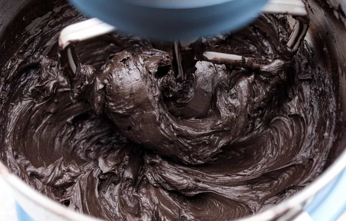 This delicious black frosting is fun to make for special occasions, especially for Halloween, seasonal treats, and desserts. It's made with black cocoa powder, which tastes just like Oreo's! The best part is that it won't dye your mouth, hands, or clothing! It's the perfect frosting for witchy cakes and other dramatic parties. Overhead shot of the black frosting being whipped in a stand mixer.