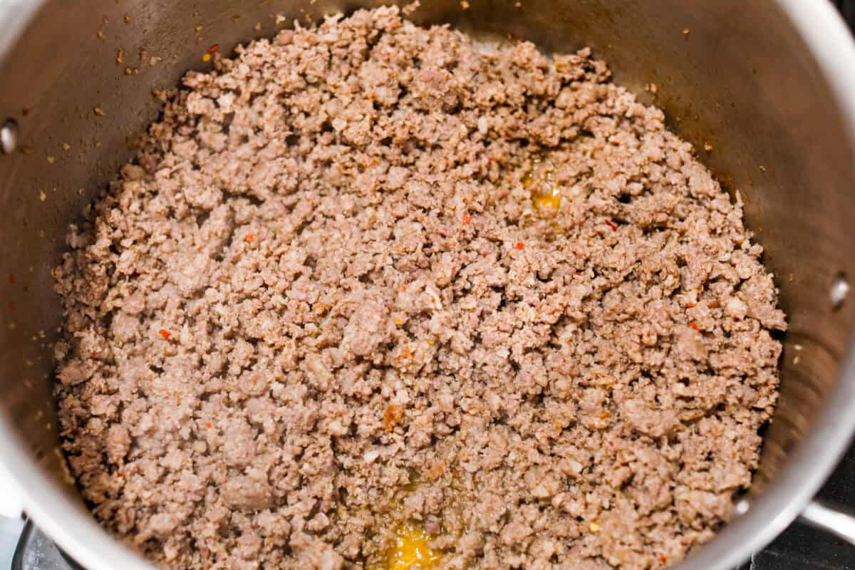 Breakfast Chili is comforting, tasty and will fill you up for hours! A combination of sausage, bacon, tomato sauce, beans, and plenty of tasty seasonings come together for a unique morning meal you will love! Top it off with fried eggs and fresh cilantro for major flavor! Overhead shot of sausage being cooked in a pan.