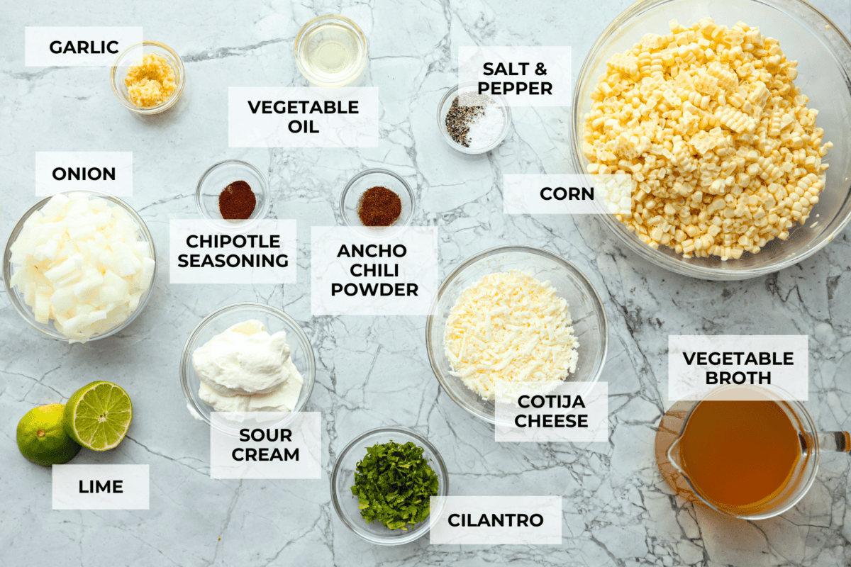 Mexican street corn soup has all the incredible flavors of street corn in a warm, comforting, delicious soup. This soup has fresh corn, lots of cotija cheese, spices, cilantro, lime juice, and sour cream to make it smooth and creamy. Overhead shot of labeled ingredients.