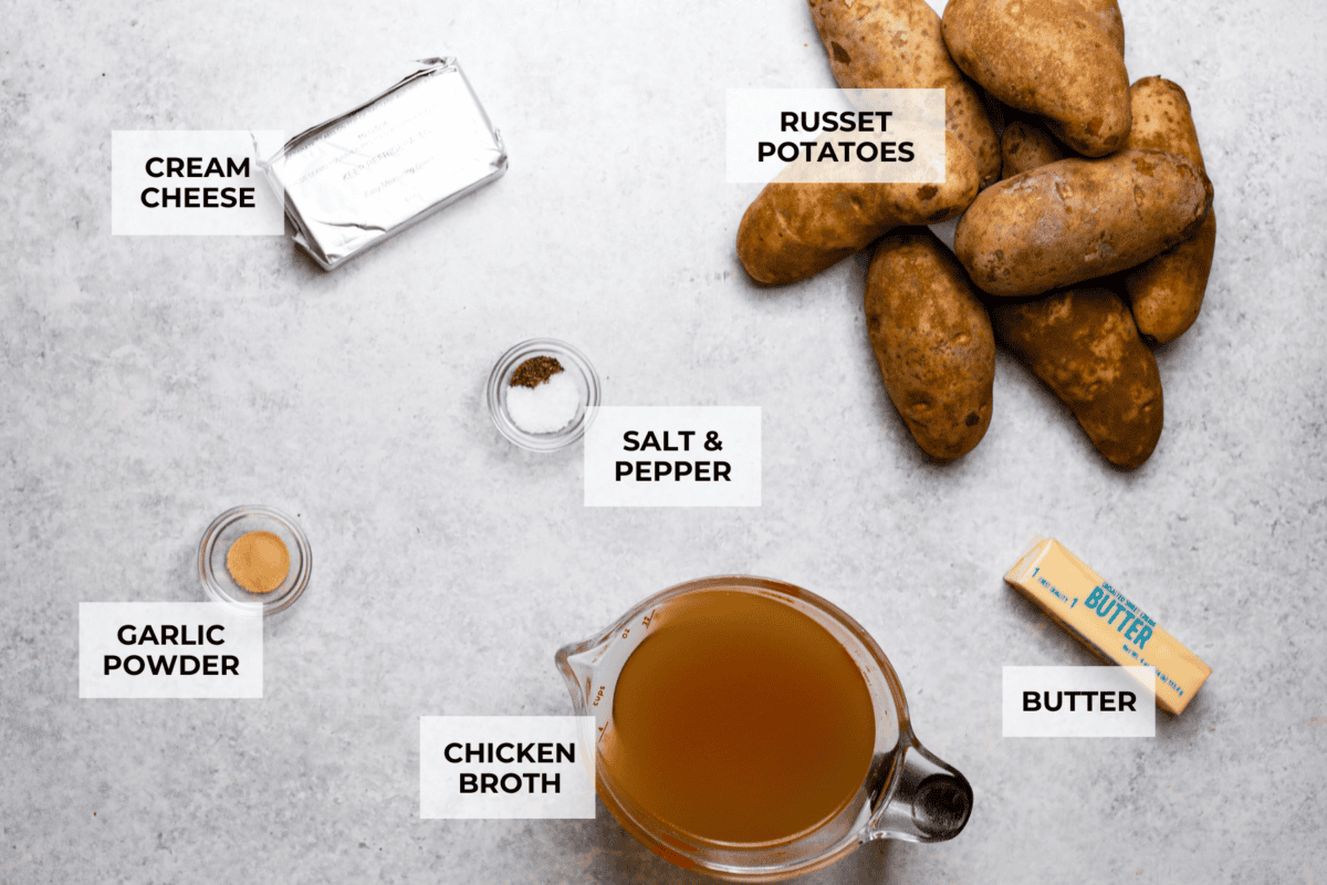 Million dollar mashed potatoes are unmatched when it comes to creamy velvety mashed potatoes. They get their intense flavors and smooth texture from letting the potatoes slow cook in chicken broth then mixing them with cream cheese, butter and garlic. Overhead shot of labeled ingredients.