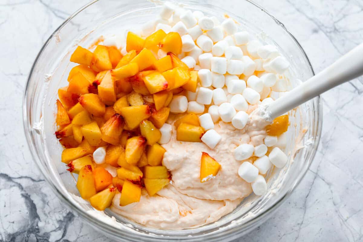 t's peach season which means you have to make this Peach Fluff Salad! It's a creamy, fruity dessert that hits all the right notes and is packed with fresh peaches! Fresh peaches and marshmallows added into the bowl for the peach fluff salad.