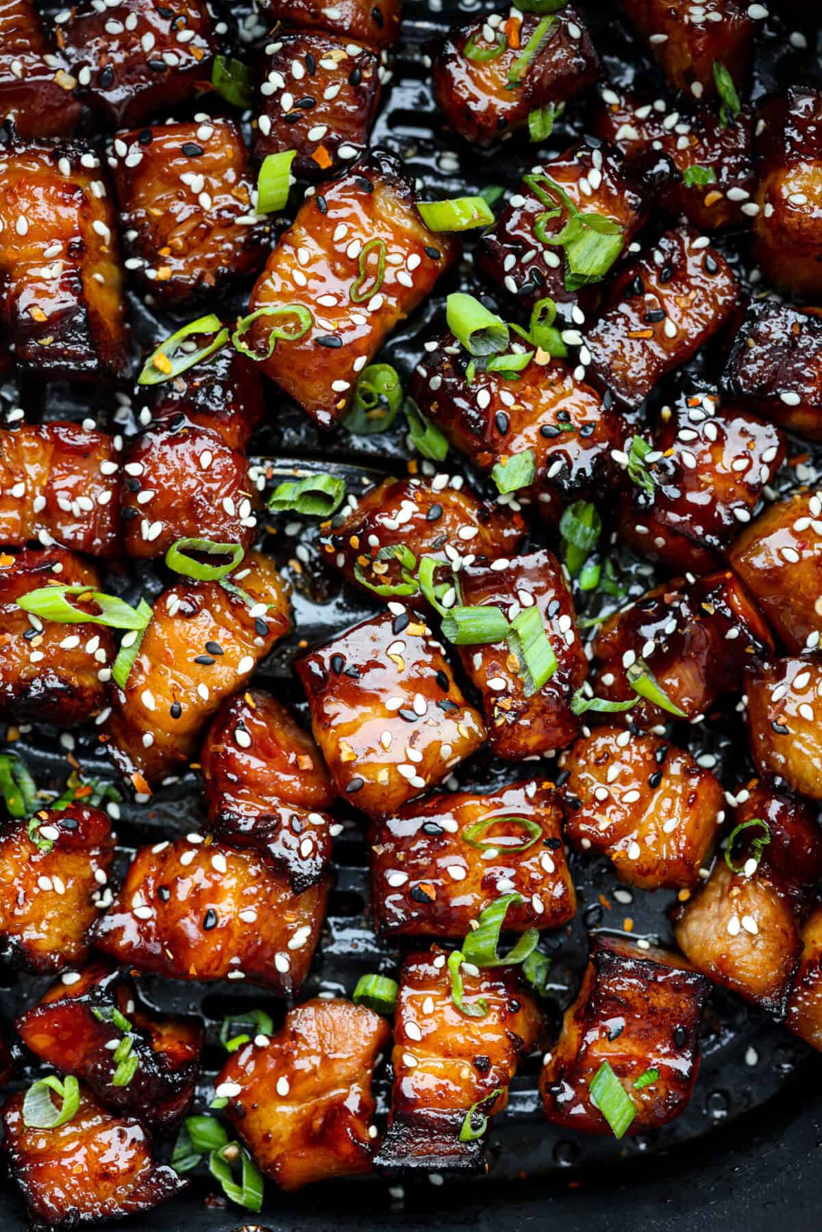 This simple air fryer pork belly recipe is great for making and enjoying this indulgent snack. It's meaty, crispy, smothered in a sticky, salty marinade that sets the flavors off perfectly! Close up shot of air fryer pork belly.